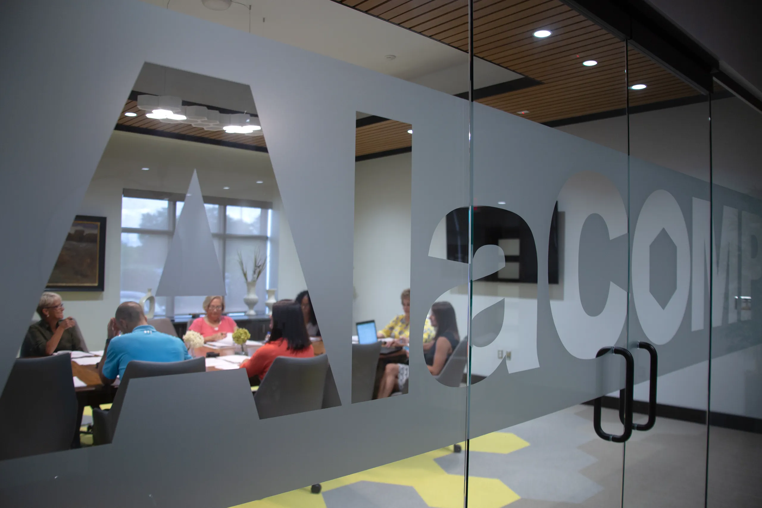 AlaCOMP team members meeting in a glass-walled conference room.